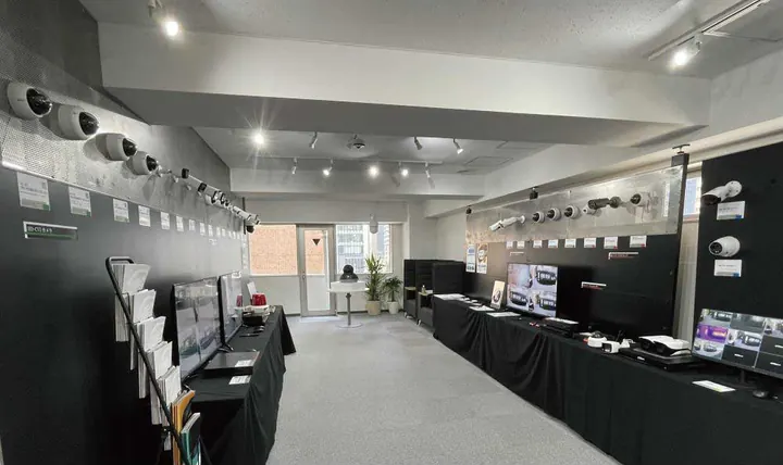 東京オフィスのショールームの全景。左右の壁にカメラが並び、黒い布を掛けた長机にモニターと録画機が置かれている